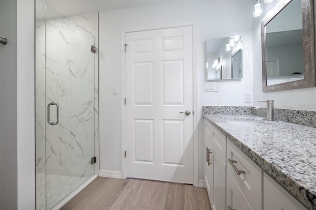 bathroom with hardwood / wood-style flooring, a shower with door, and vanity