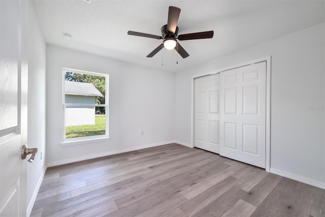 unfurnished bedroom with light hardwood / wood-style flooring, a closet, and ceiling fan