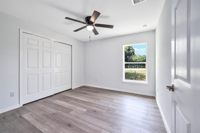 unfurnished bedroom with a textured ceiling, ceiling fan, a closet, and light hardwood / wood-style flooring