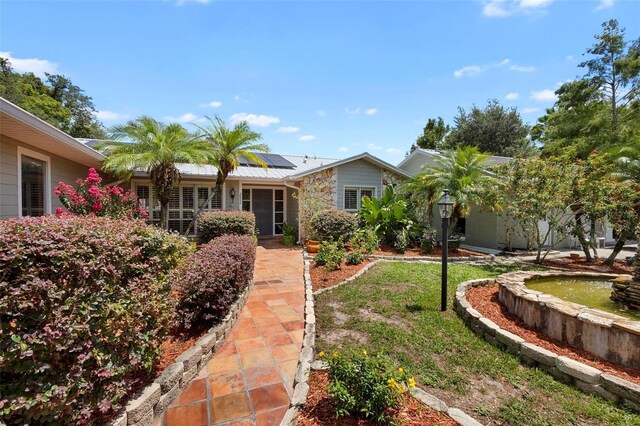 ranch-style home with a front yard and solar panels