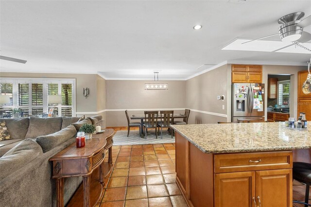 kitchen featuring a healthy amount of sunlight, ceiling fan, a skylight, and stainless steel refrigerator with ice dispenser