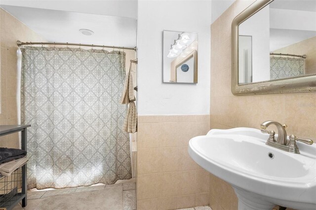 bathroom with tile walls, a shower with curtain, and sink