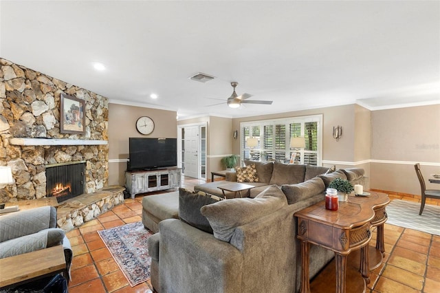 living room featuring ceiling fan, light tile patterned floors, ornamental molding, and a stone fireplace