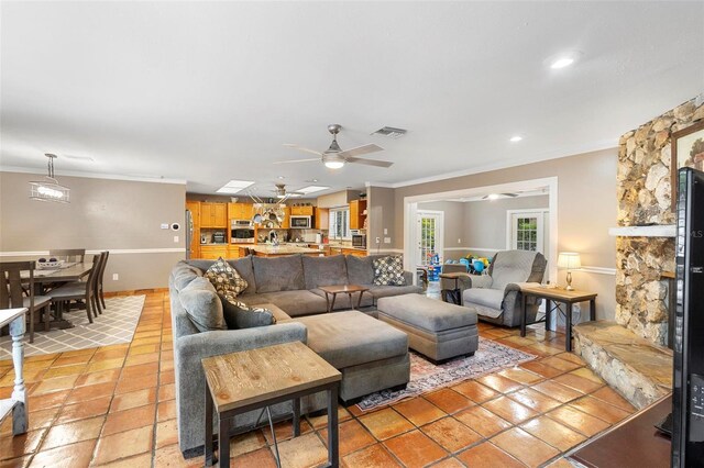 living room featuring ceiling fan, a fireplace, ornamental molding, and light tile patterned flooring