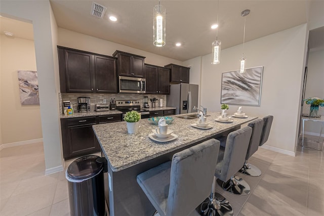 kitchen featuring appliances with stainless steel finishes, a breakfast bar, and an island with sink