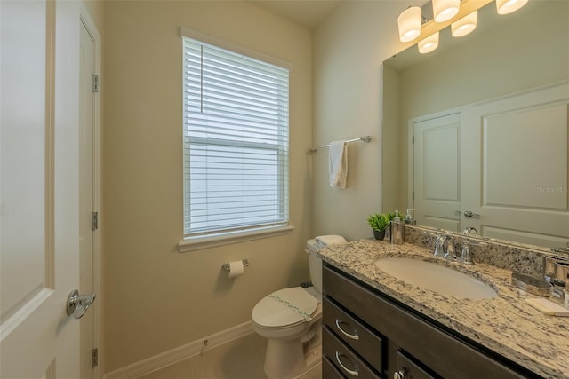 half bathroom with tile patterned floors, toilet, vanity, and baseboards