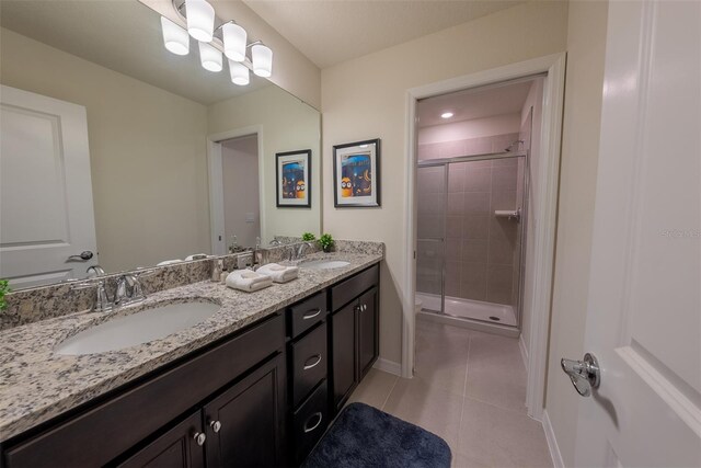 bathroom featuring dual bowl vanity, a tile shower, and tile patterned floors