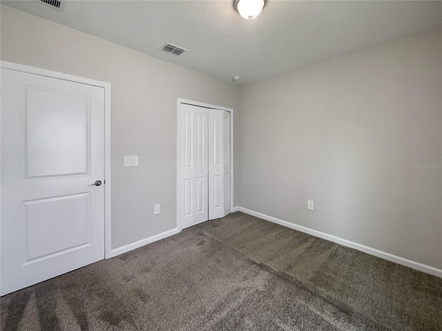 unfurnished bedroom with a closet and dark colored carpet