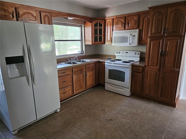 kitchen with dark tile patterned flooring, white appliances, and sink