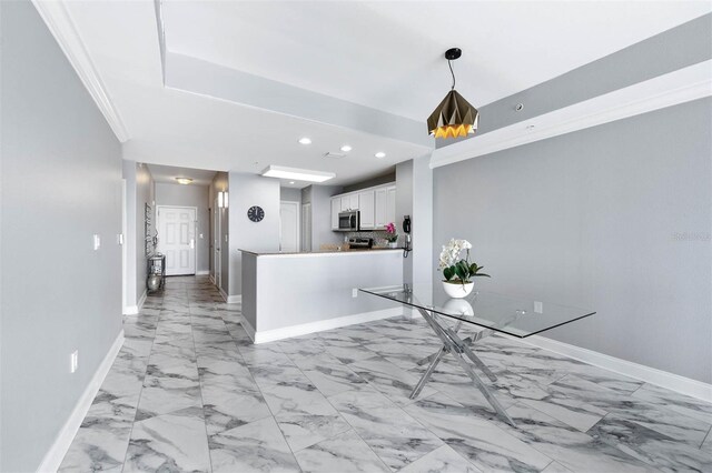 kitchen with decorative light fixtures, kitchen peninsula, ornamental molding, and white cabinetry