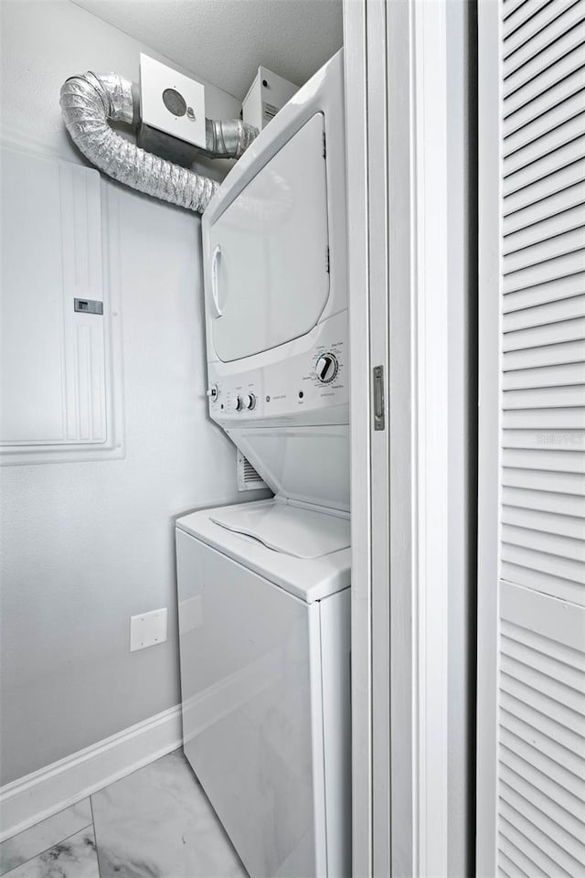 clothes washing area featuring stacked washer and dryer and electric panel