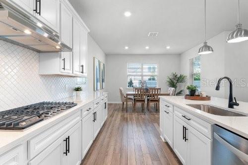 kitchen featuring sink, decorative light fixtures, decorative backsplash, white cabinets, and appliances with stainless steel finishes