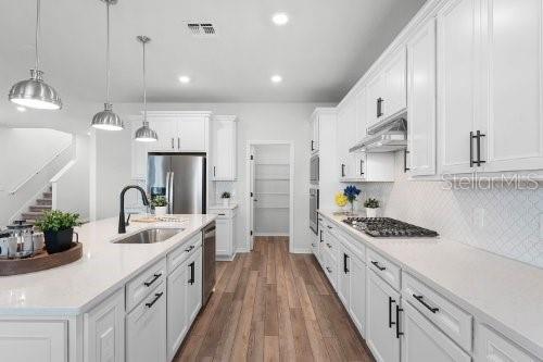 kitchen featuring pendant lighting, sink, white cabinets, and stainless steel appliances