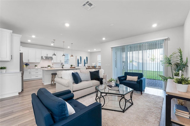 living room featuring sink and light hardwood / wood-style floors