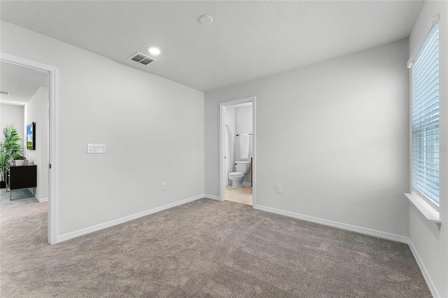 unfurnished bedroom with ensuite bathroom and light colored carpet