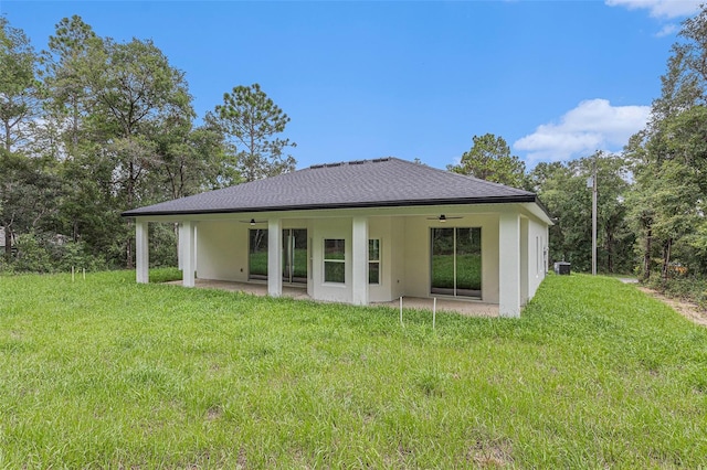 rear view of property featuring ceiling fan, a lawn, and a patio area