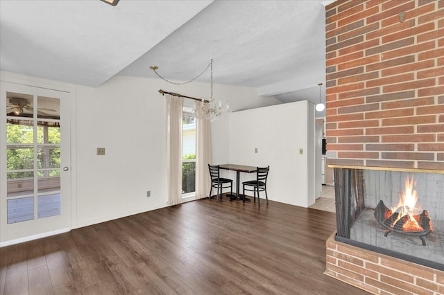 unfurnished living room featuring a notable chandelier, dark hardwood / wood-style floors, a fireplace, and vaulted ceiling