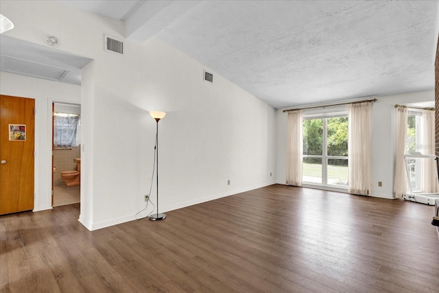 spare room with beamed ceiling and dark hardwood / wood-style floors