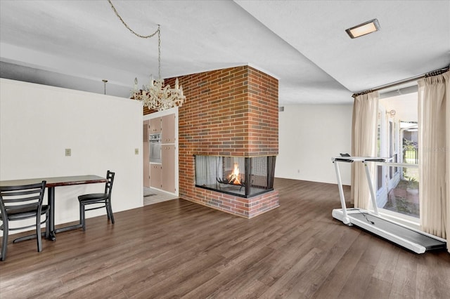 unfurnished living room with a fireplace, dark wood-type flooring, and a chandelier