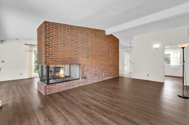 unfurnished living room with a brick fireplace, a textured ceiling, lofted ceiling with beams, an inviting chandelier, and dark hardwood / wood-style floors