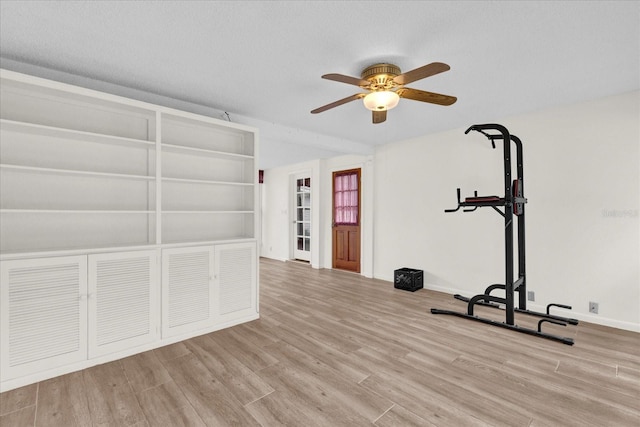 exercise area with a textured ceiling, light hardwood / wood-style flooring, and ceiling fan