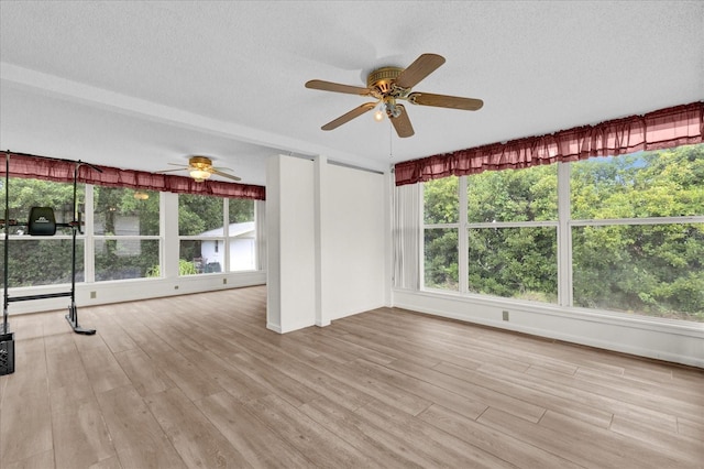 unfurnished living room with ceiling fan, light hardwood / wood-style floors, and a textured ceiling