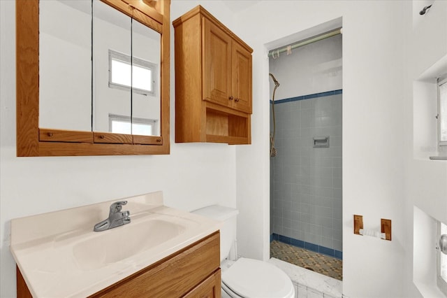 bathroom with toilet, vanity, and tiled shower