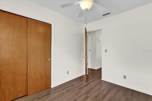 unfurnished bedroom with ceiling fan, a closet, and dark wood-type flooring