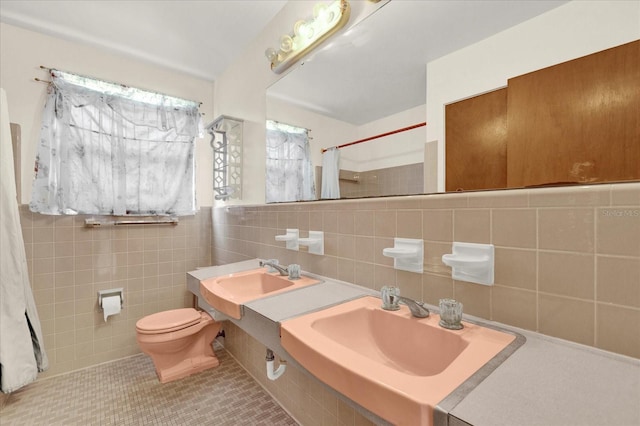 bathroom with tile patterned floors, sink, tile walls, and toilet