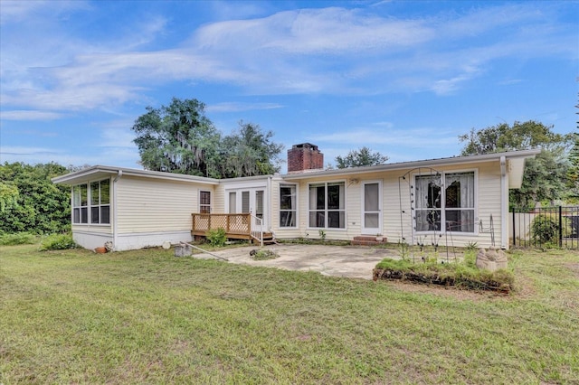 back of property featuring a lawn, a patio, and a wooden deck