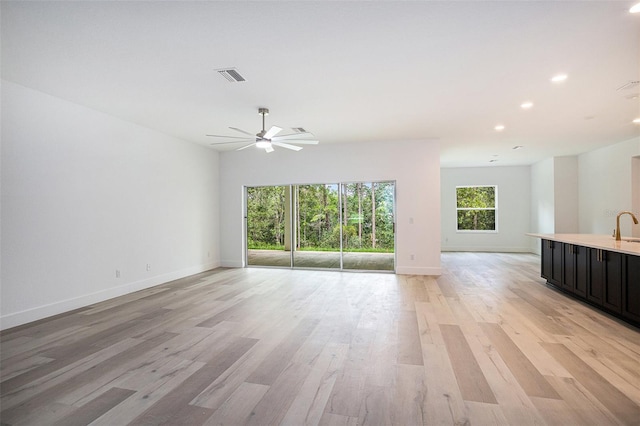 unfurnished living room with light wood-type flooring and ceiling fan