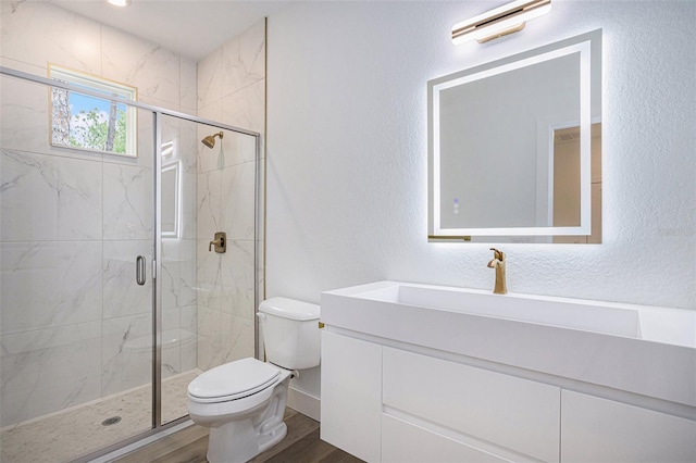 bathroom featuring a shower with shower door, vanity, wood-type flooring, and toilet