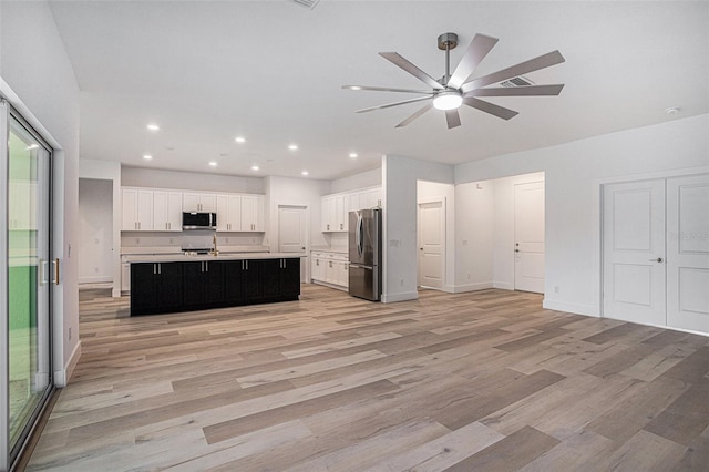 kitchen with ceiling fan, stainless steel appliances, light wood-type flooring, an island with sink, and sink