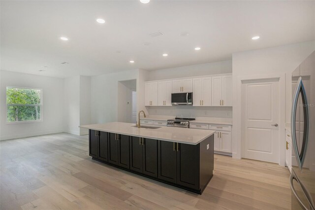 kitchen with sink, appliances with stainless steel finishes, light hardwood / wood-style floors, and white cabinetry