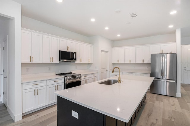 kitchen with appliances with stainless steel finishes, a center island with sink, and light hardwood / wood-style floors