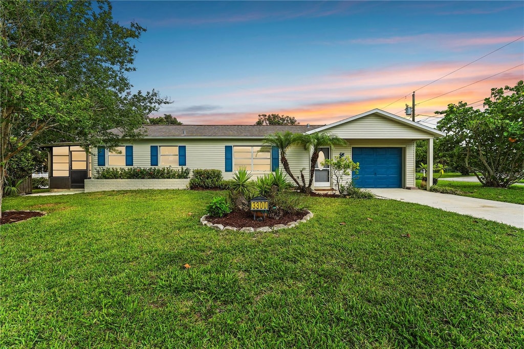 single story home featuring a garage and a lawn