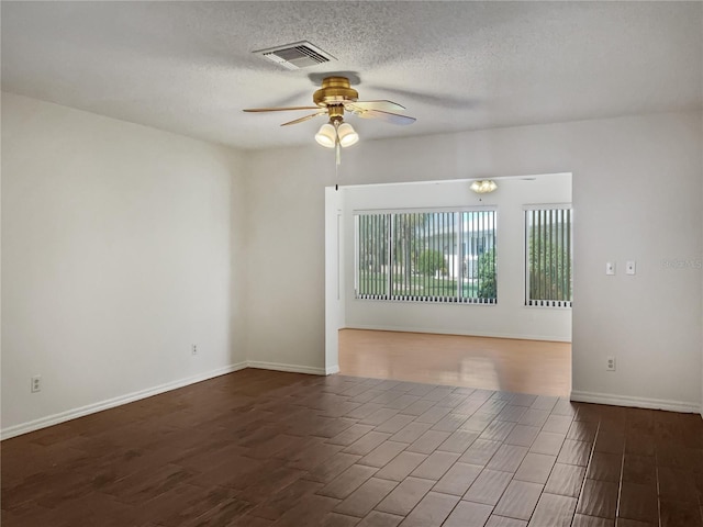 empty room featuring dark hardwood / wood-style floors, ceiling fan, and a textured ceiling