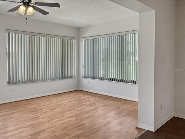 unfurnished room with ceiling fan, light wood-type flooring, and a textured ceiling