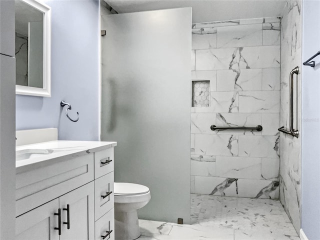 bathroom with a tile shower, vanity, and toilet