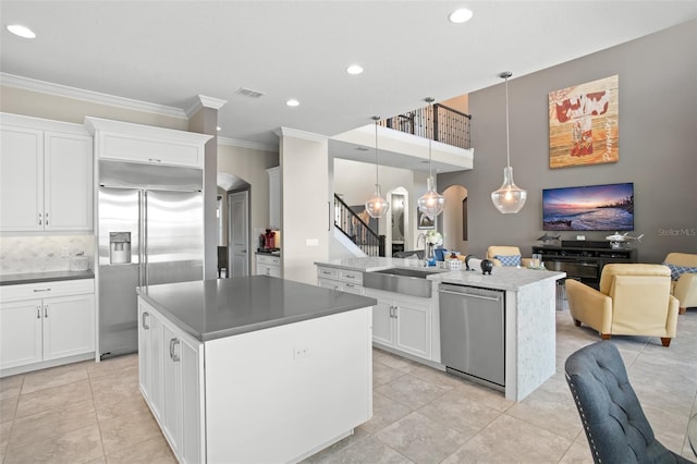 kitchen with pendant lighting, a center island, sink, white cabinetry, and stainless steel appliances