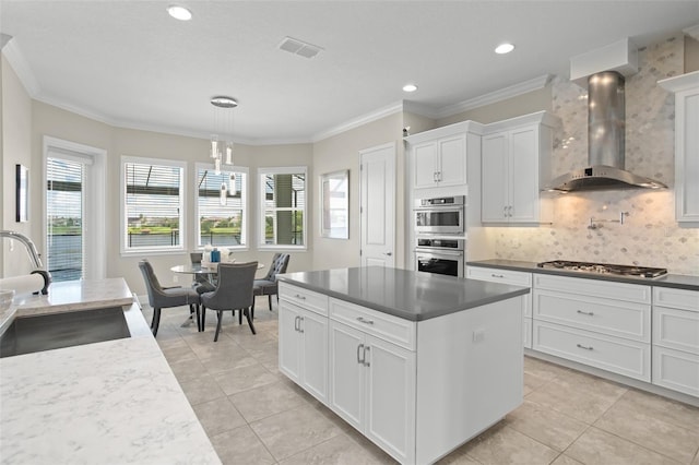 kitchen featuring decorative backsplash, appliances with stainless steel finishes, sink, wall chimney range hood, and white cabinetry