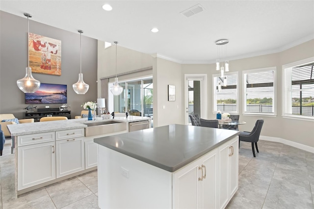 kitchen with a healthy amount of sunlight, a center island with sink, white cabinets, and pendant lighting