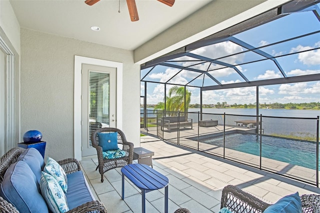 view of patio with outdoor lounge area, ceiling fan, a water view, and glass enclosure