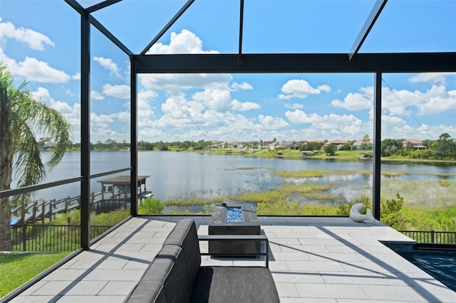 view of patio / terrace with a lanai, a water view, and an outdoor fire pit