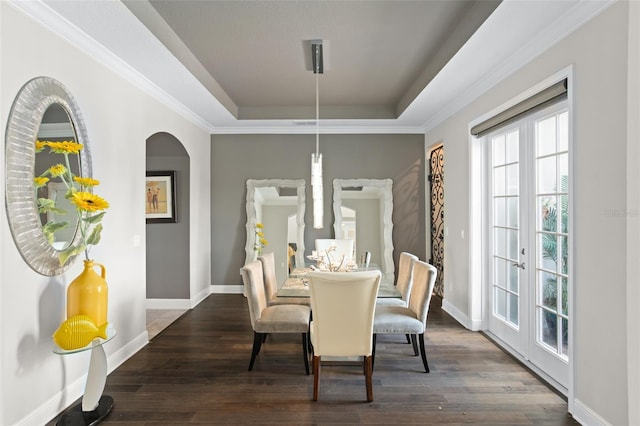 dining space featuring french doors, a tray ceiling, crown molding, and dark wood-type flooring