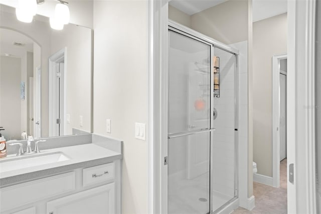 bathroom featuring tile patterned floors, a shower with door, vanity, and toilet