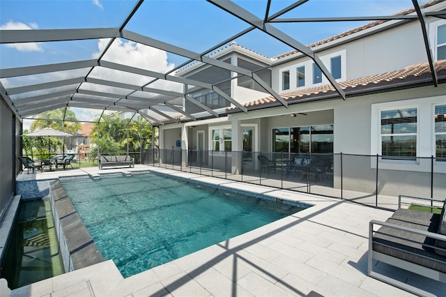 view of pool with glass enclosure, a patio area, and ceiling fan