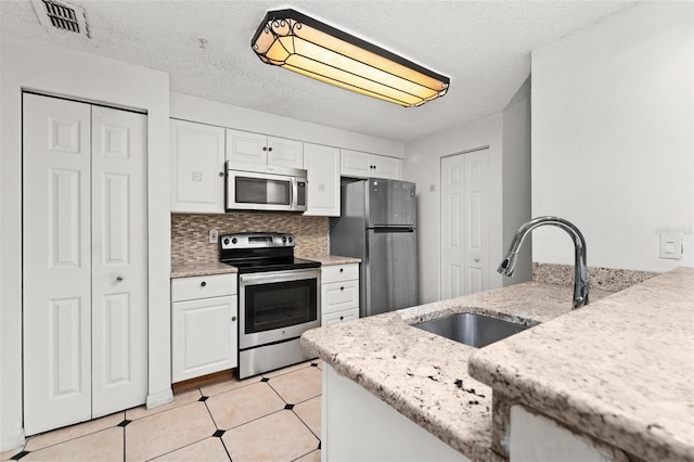 kitchen featuring sink, white cabinets, appliances with stainless steel finishes, and a textured ceiling