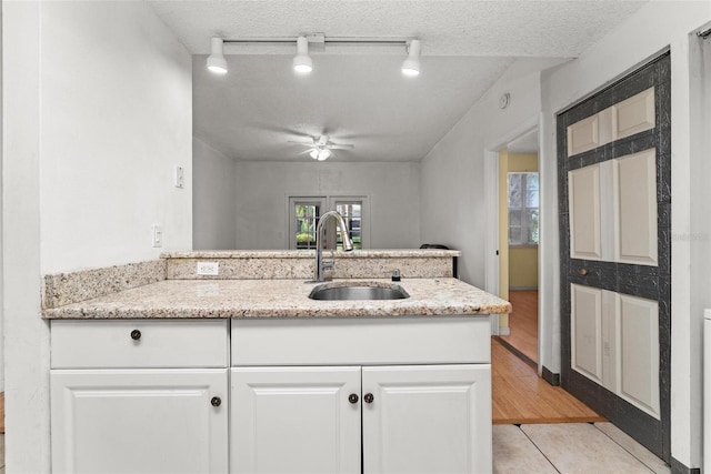 kitchen featuring sink, a textured ceiling, light tile patterned floors, and white cabinetry