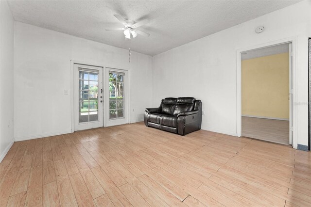 unfurnished room featuring a textured ceiling, light hardwood / wood-style flooring, ceiling fan, and french doors